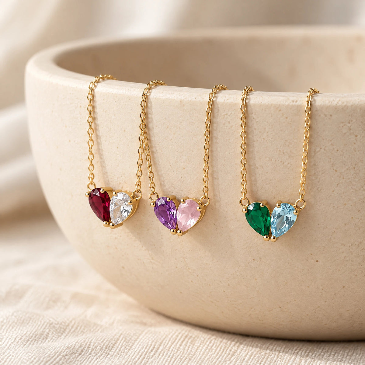Three Elora Necklaces with different birthstone pairs hanging on a stone bowl