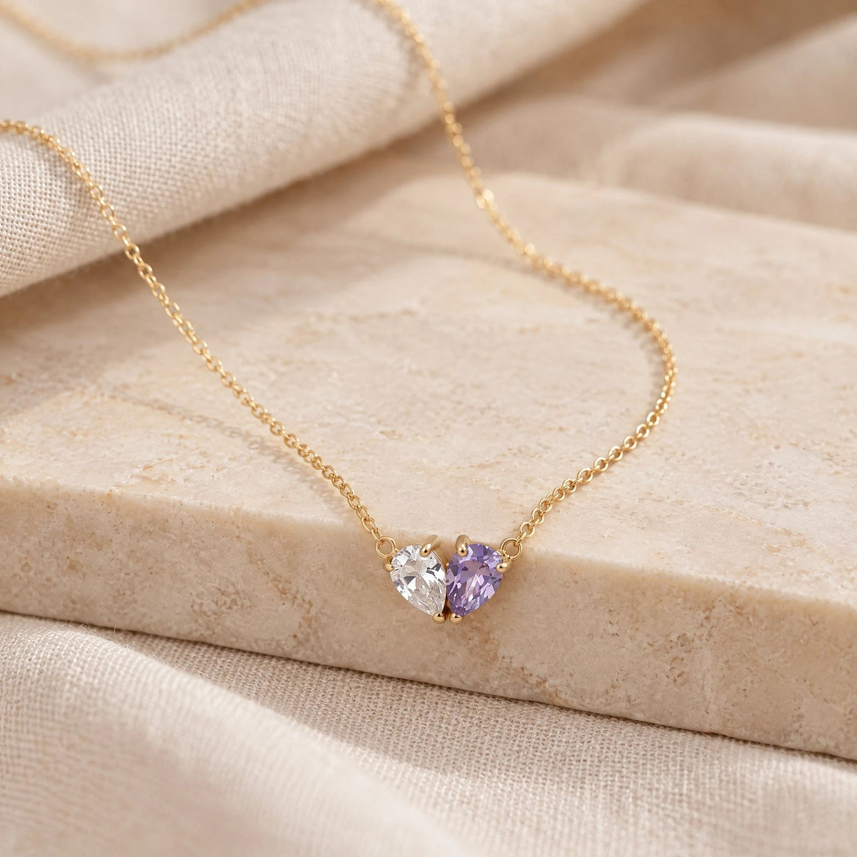 Elora Necklace with a white and an amethyst birthstone on a cream stone