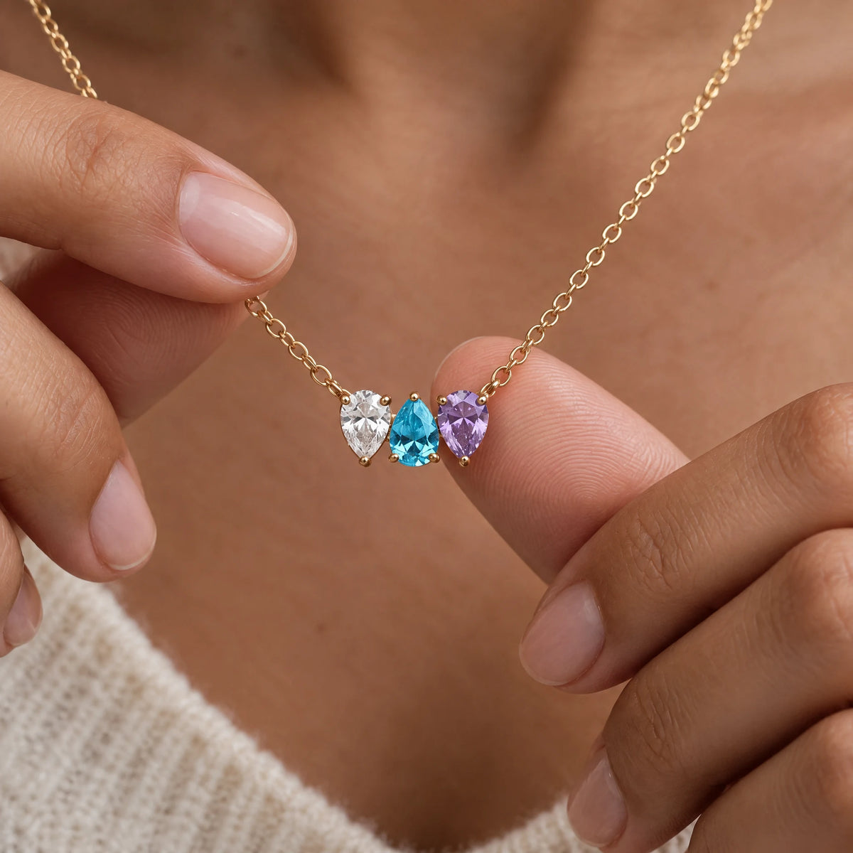 Kindred Necklace in gold with three birthstones, held between two fingers