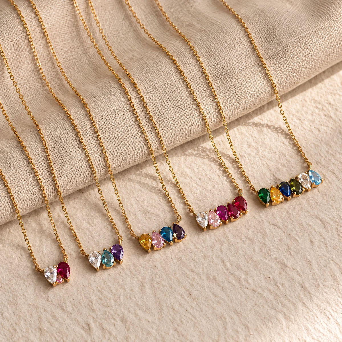 Five Kindred Necklaces with two to six birthstones laid on linen