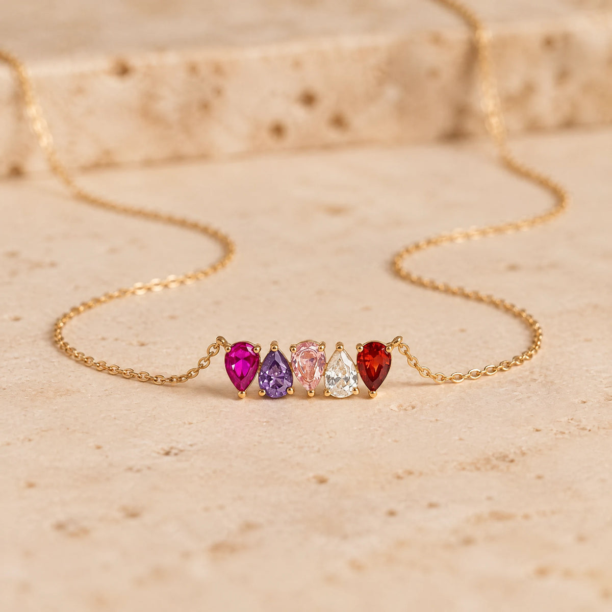 Kindred Necklace with five birthstones side by side on travertine