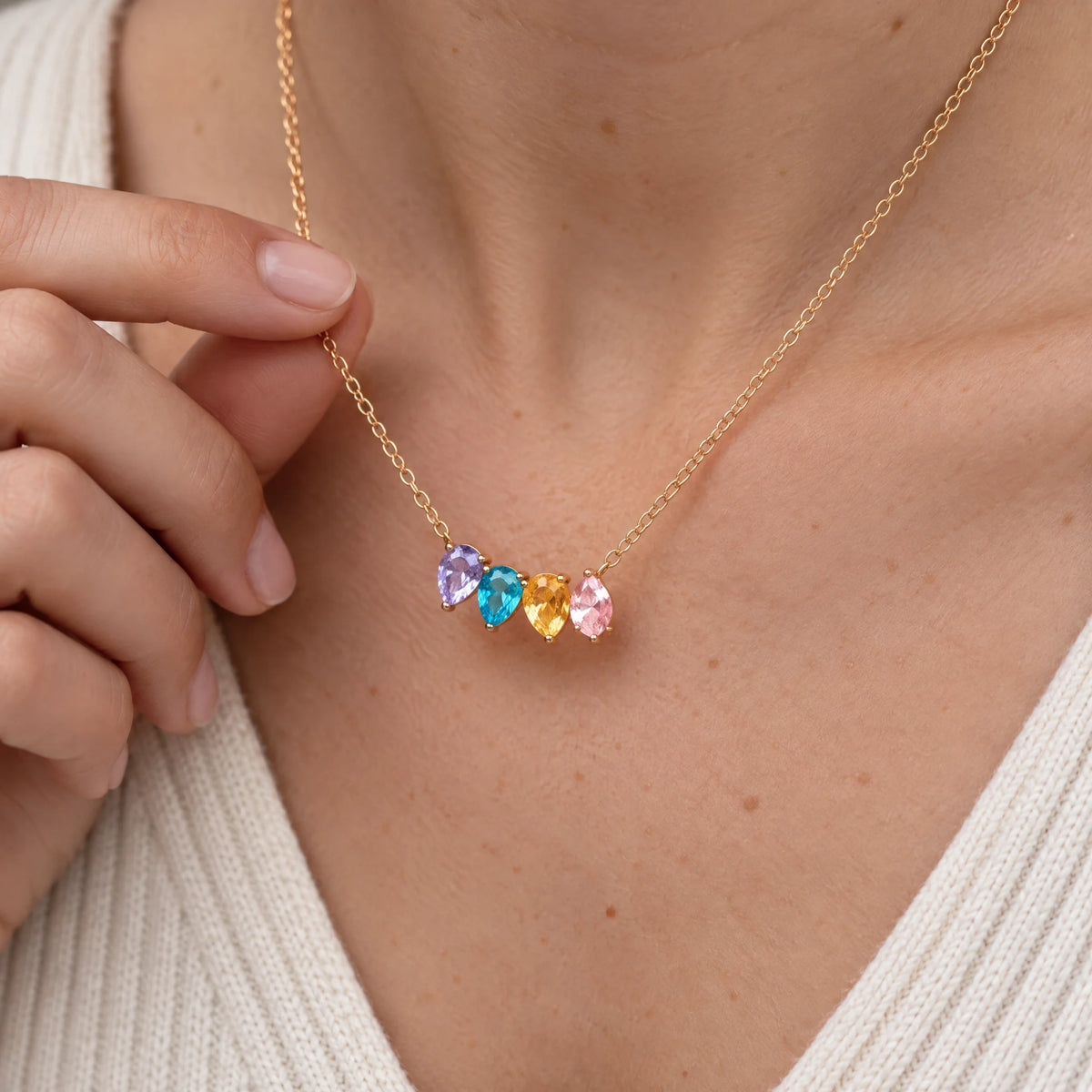 Woman holding her Kindred Necklace with four birthstones